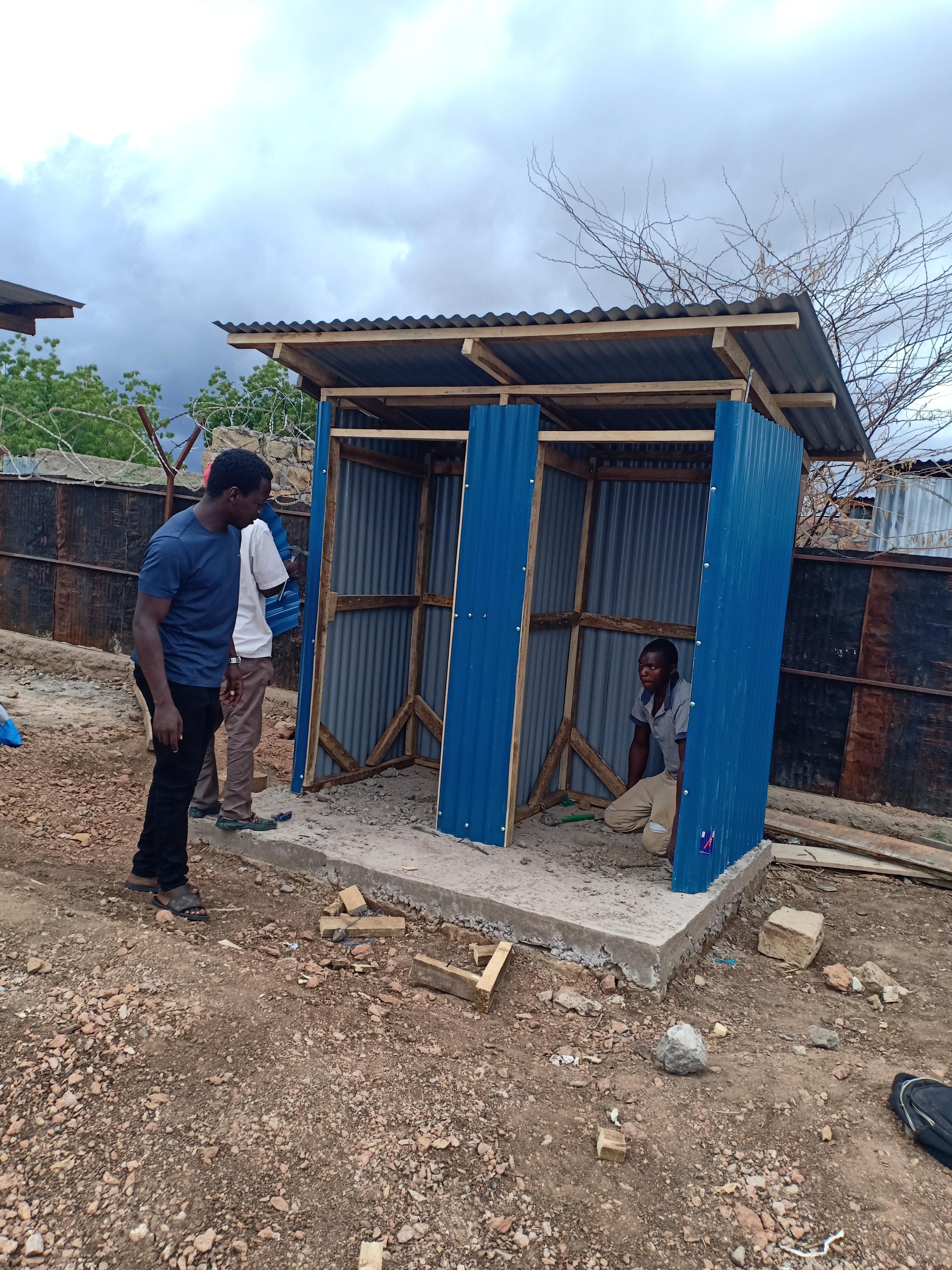 men constructing a blue metal structure in a rural area