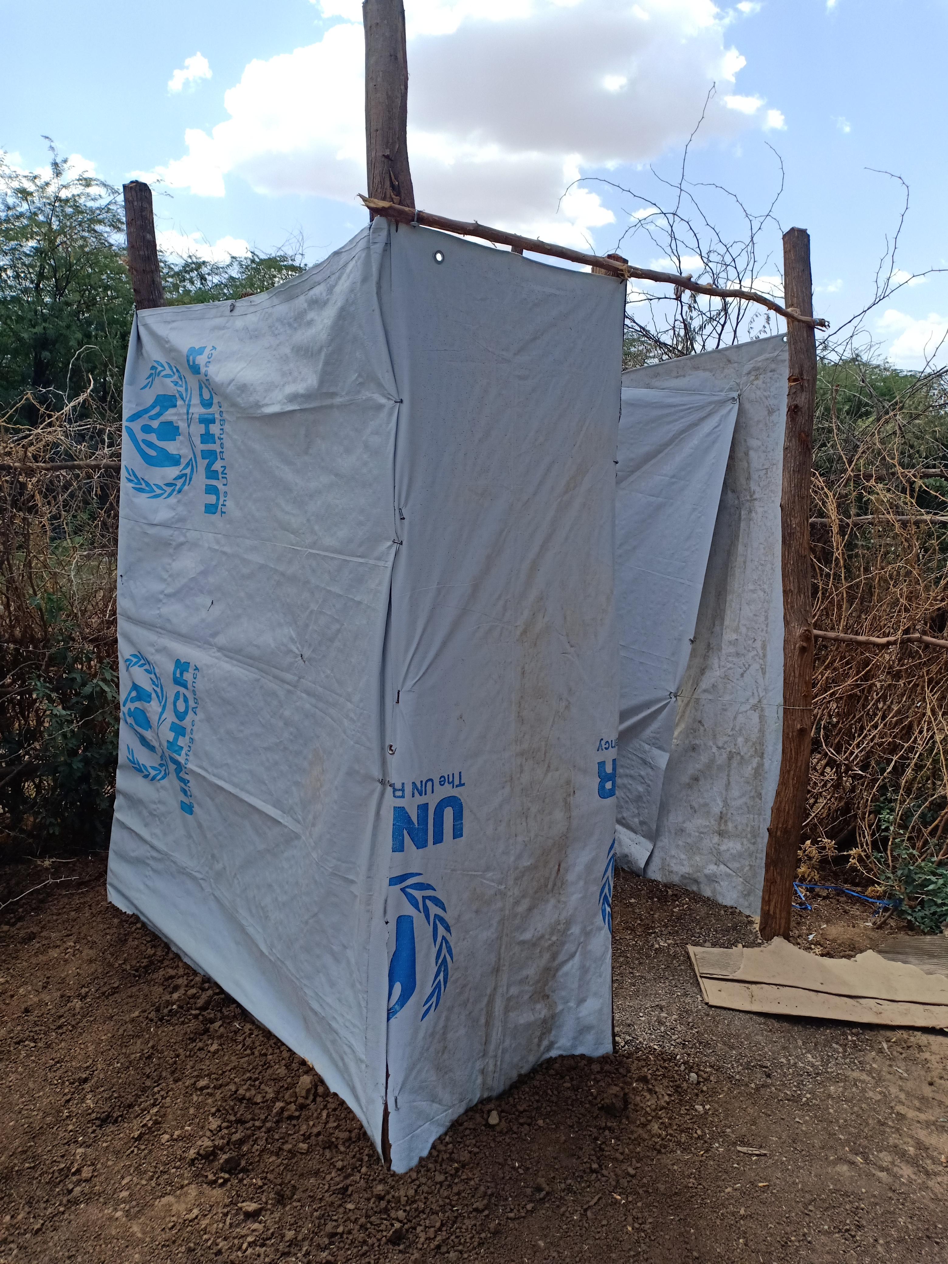 temporary sanitation shelter made from UNHCR materials in remote area